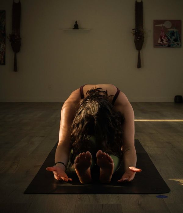 Woman in a focused yoga pose in a dark, serene environment.